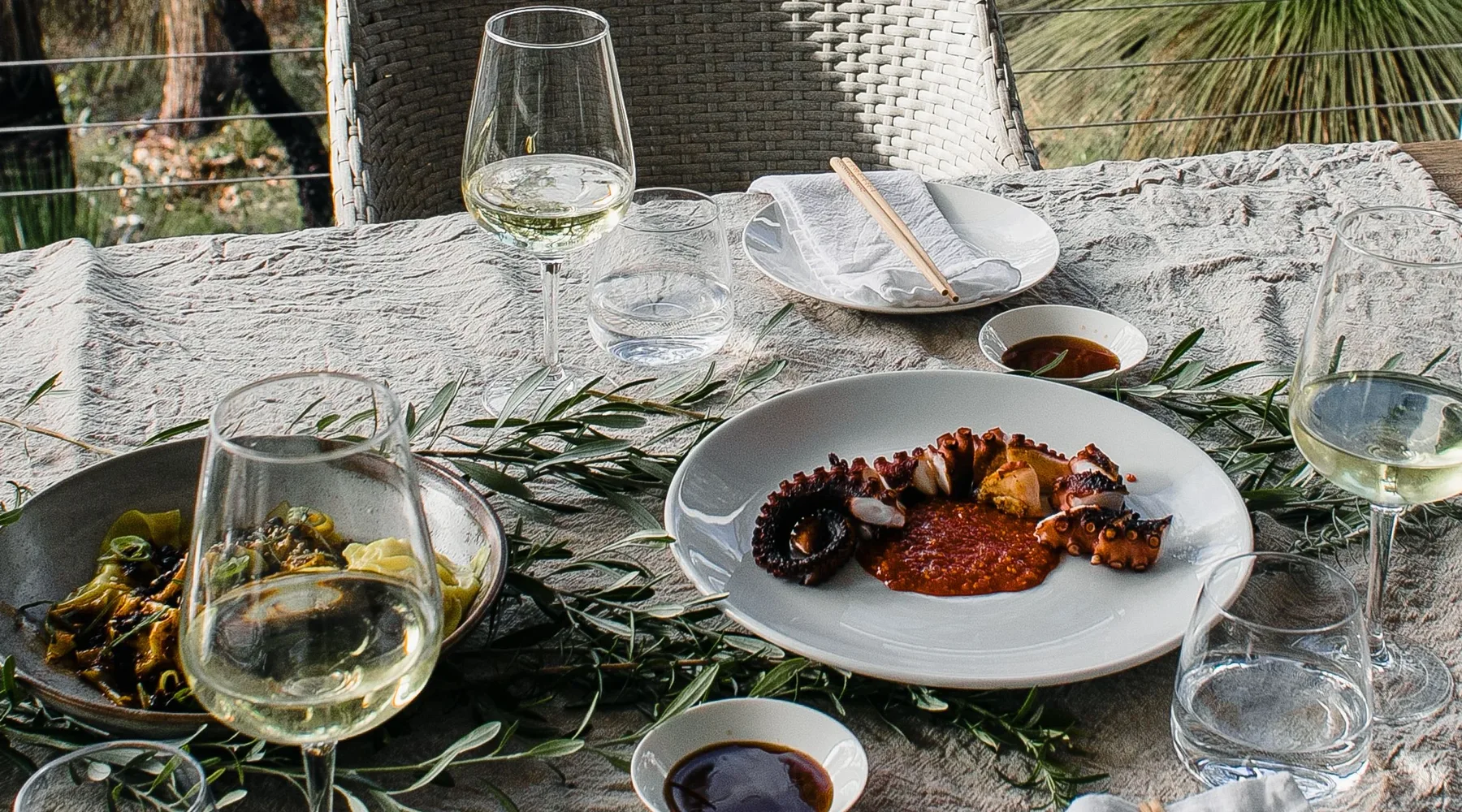 Outdoor seafood table with regional white wine and a wooded Central Coast setting
