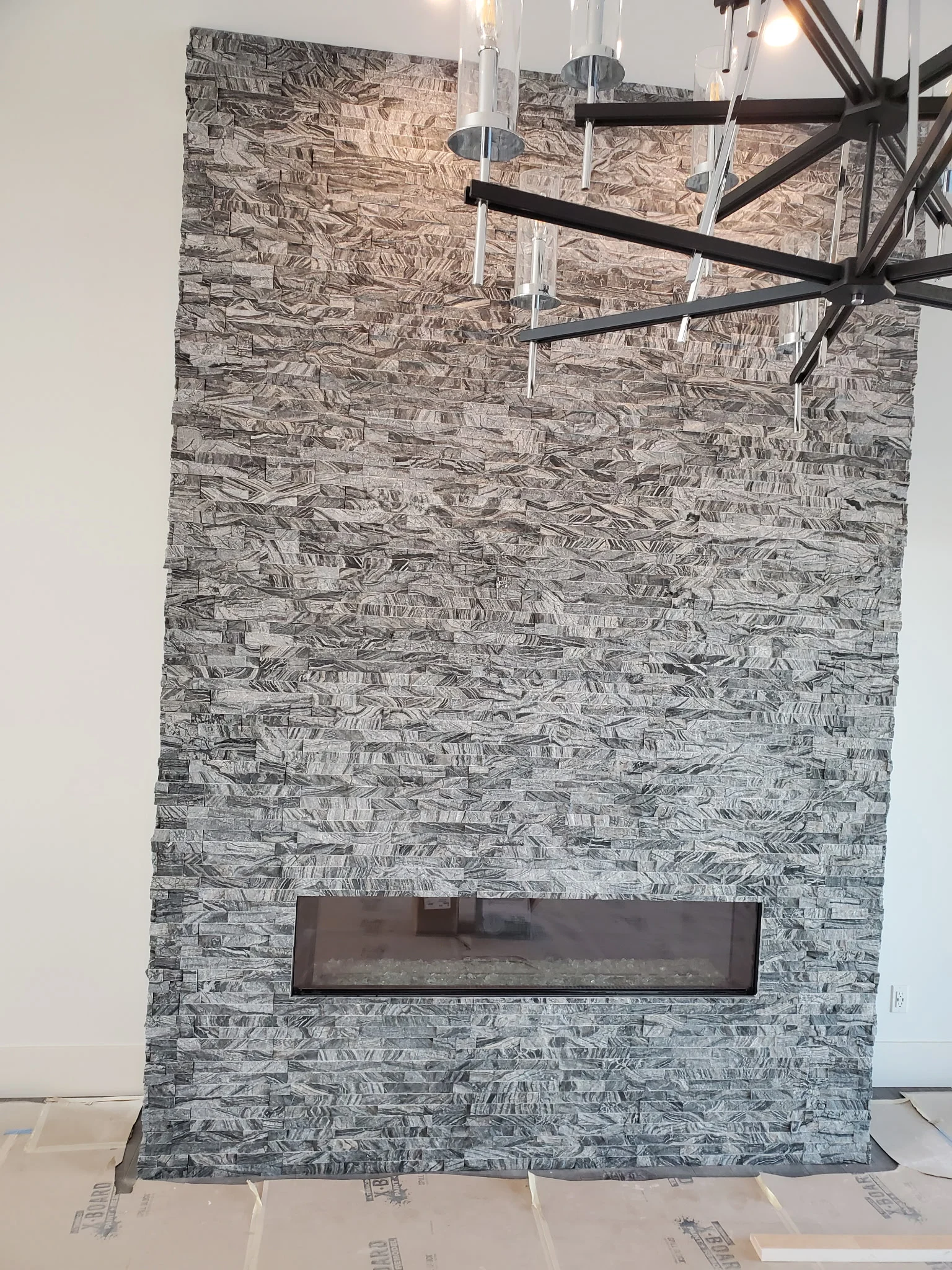 Floor-to-ceiling stacked stone wall with a linear fireplace
