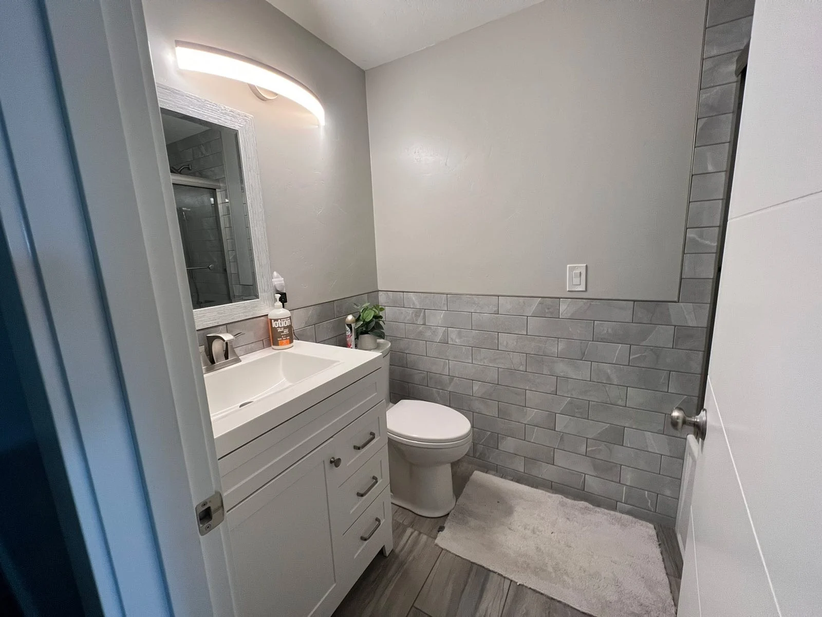 Bathroom with gray tile wainscot behind the vanity and toilet