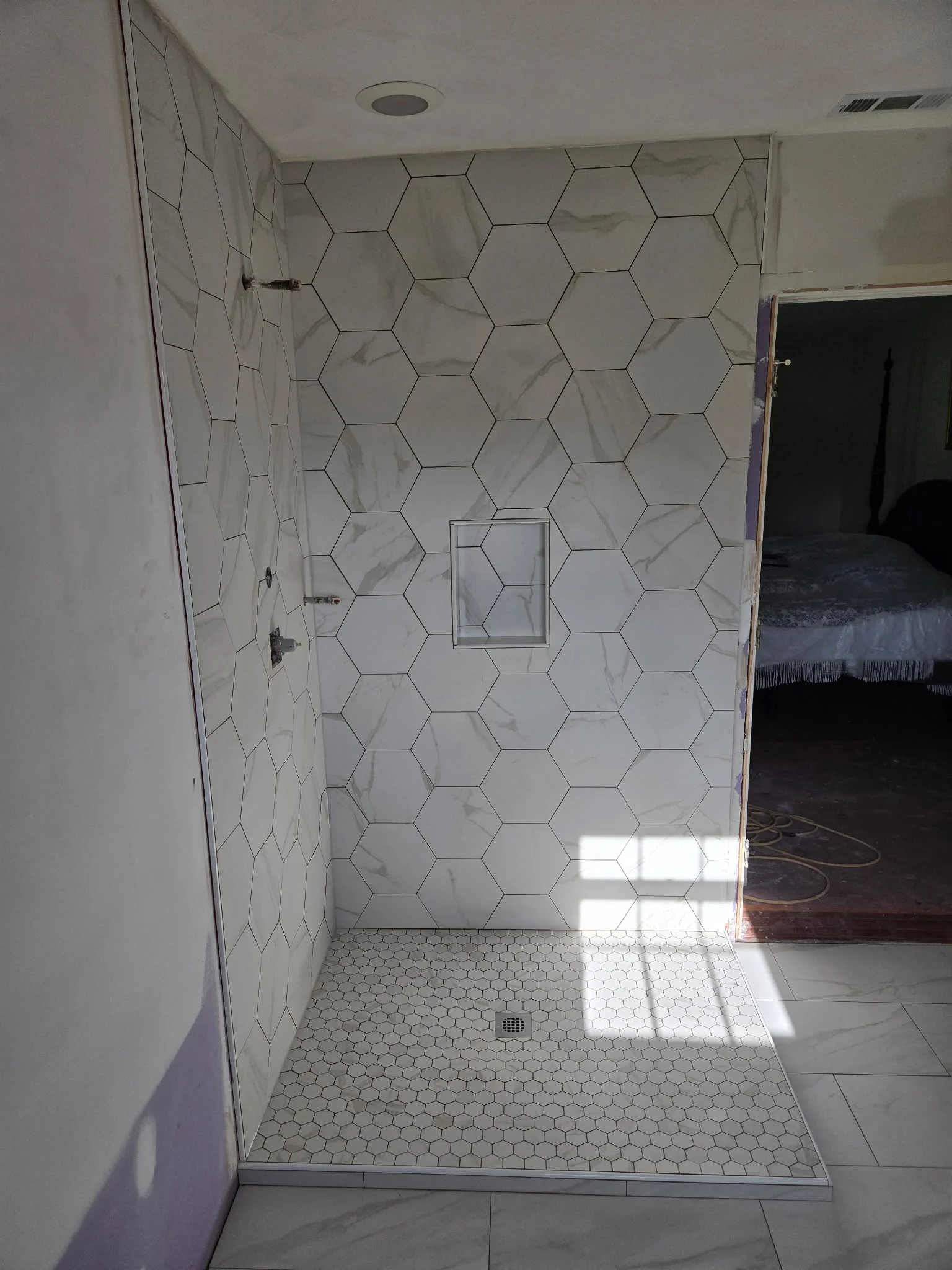 Walk-in shower with large hexagon wall tile, a recessed niche and a small hexagon mosaic floor