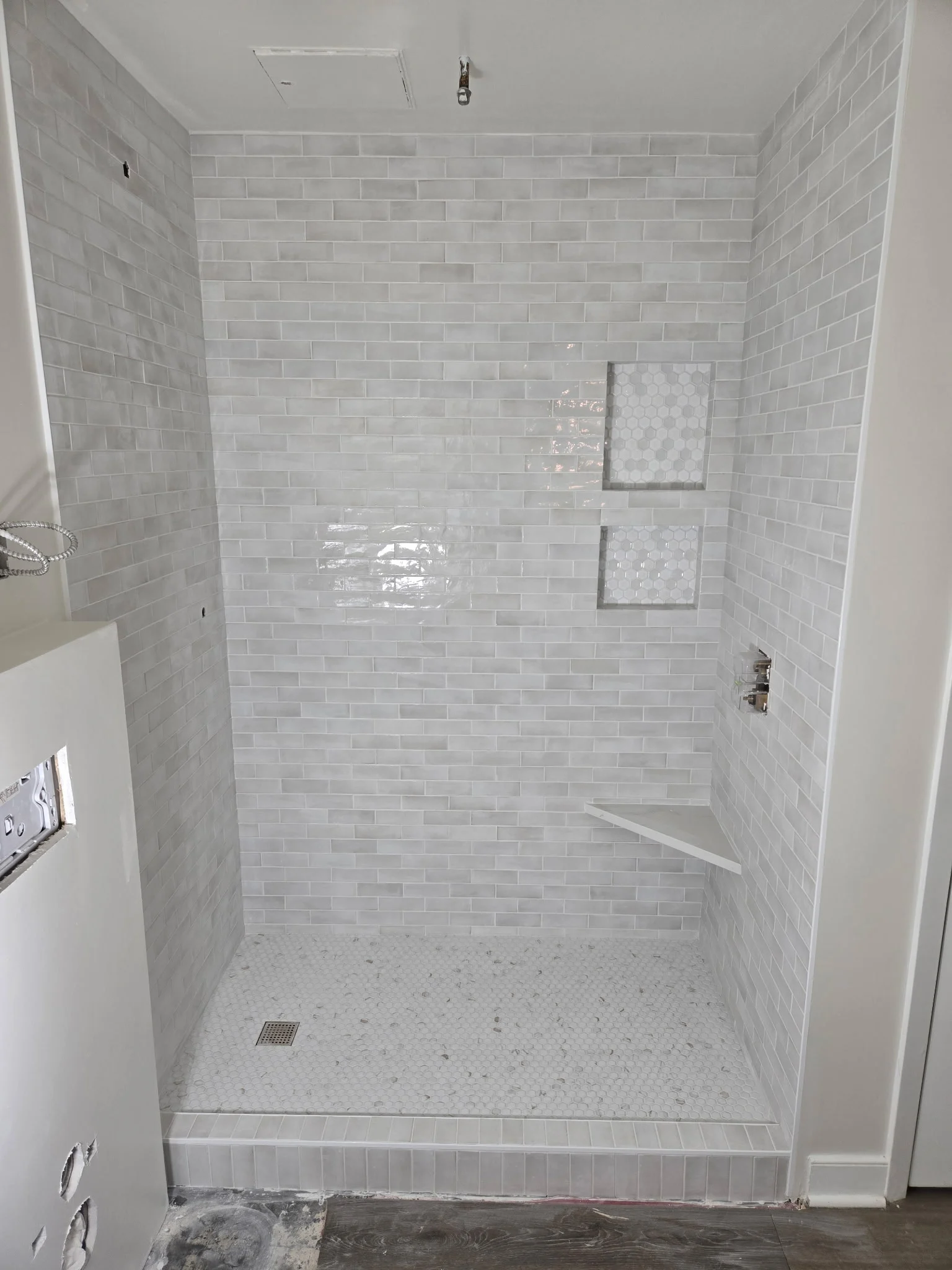 Walk-in shower in white tile with two niches and a corner shelf