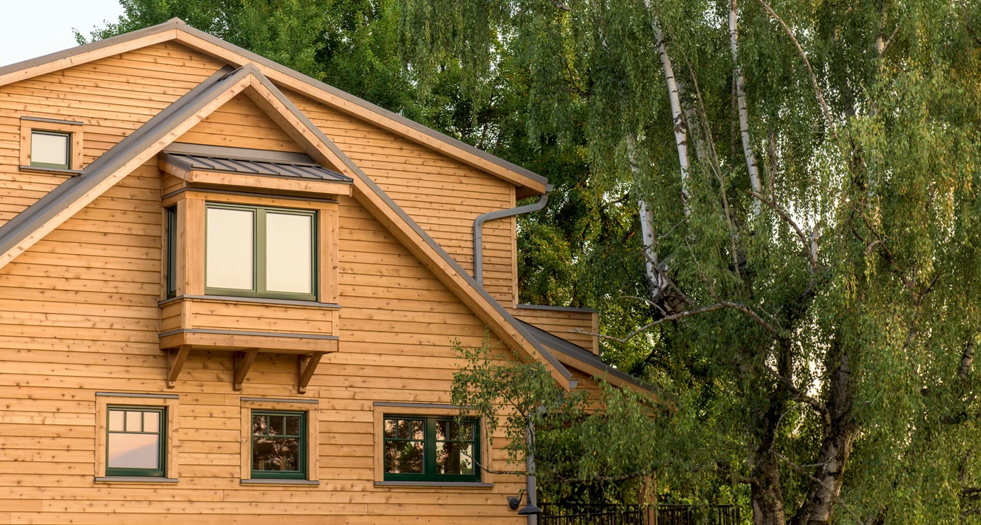 Wood-clad home beneath tall trees