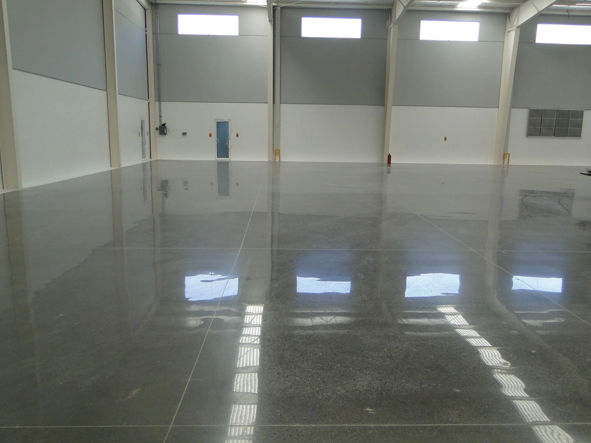 Gray concrete floor reflecting high windows in an industrial interior