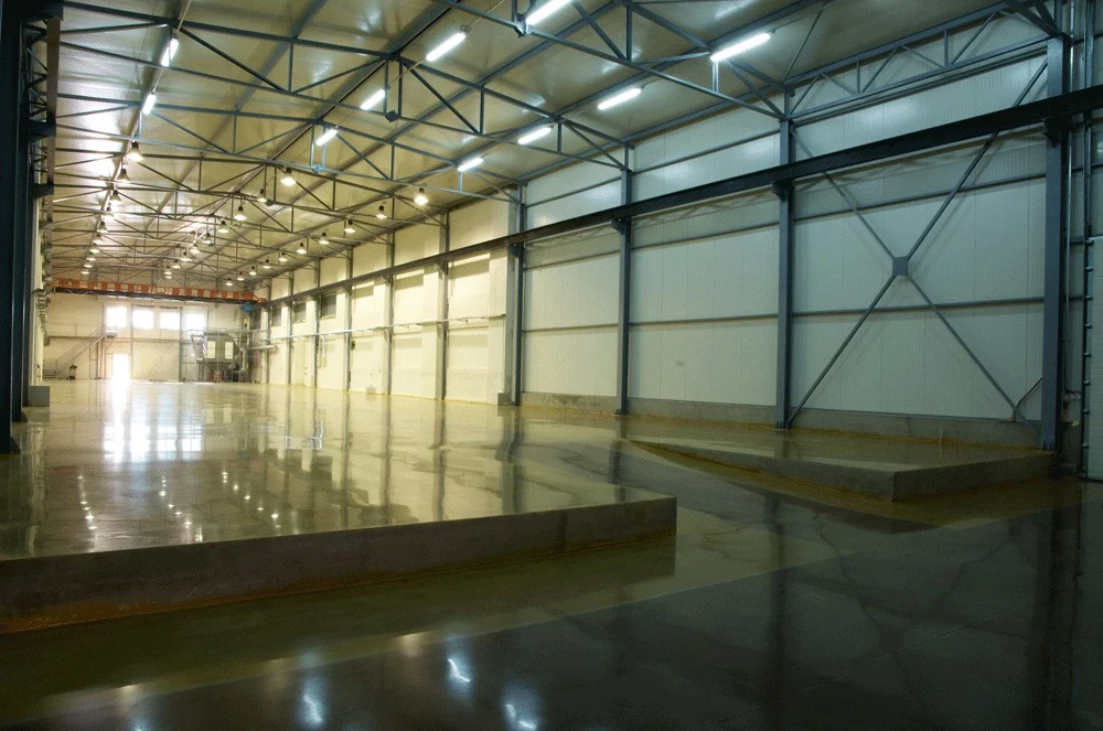 Concrete Masters v2 Reflective concrete floor beneath steel roof trusses in a large industrial interior
