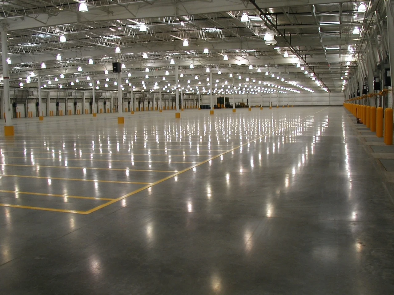 Large warehouse floor with yellow markings and reflected ceiling lights