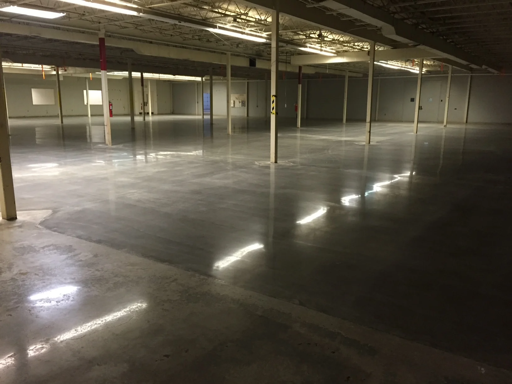 Reflective concrete floor in an open industrial interior with support columns