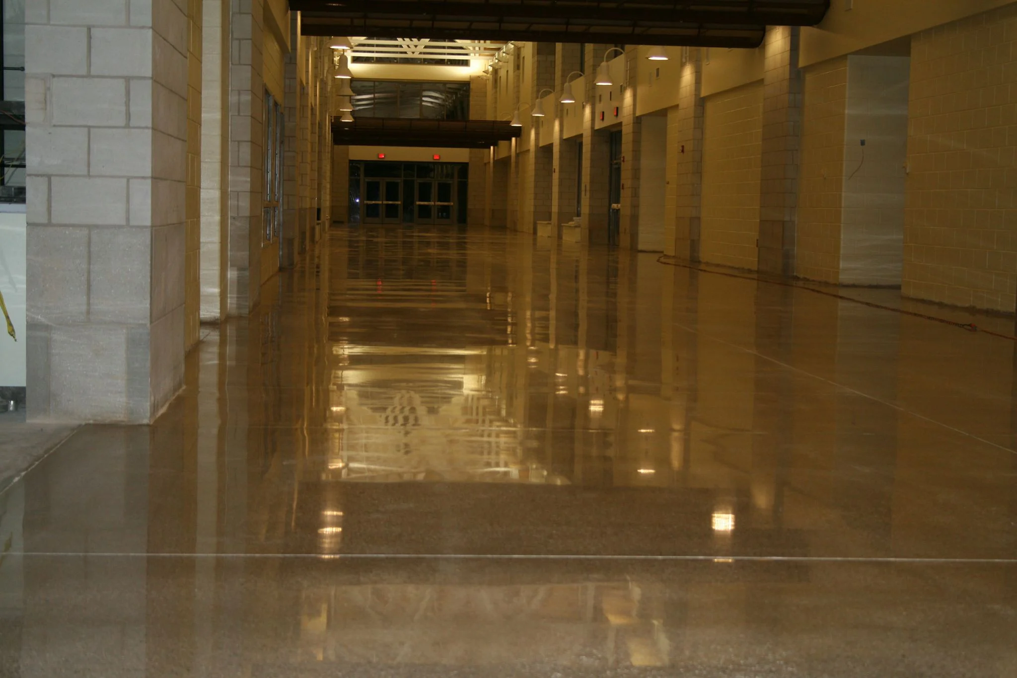 Reflective brown floor in a corridor with block walls and overhead lights