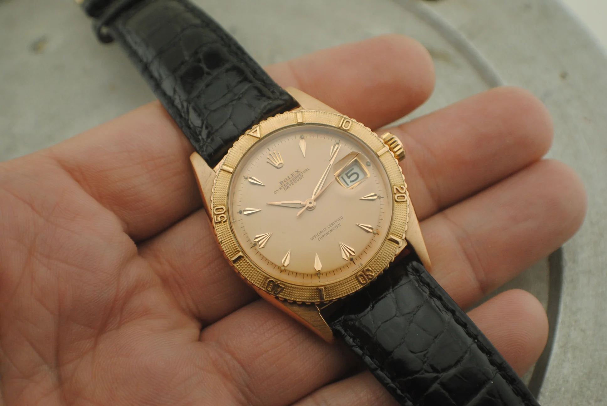 In-hand crystal-on view of the Rolex Thunderbird 6309 showing its pink dial, applied markers, bezel and pink gold case