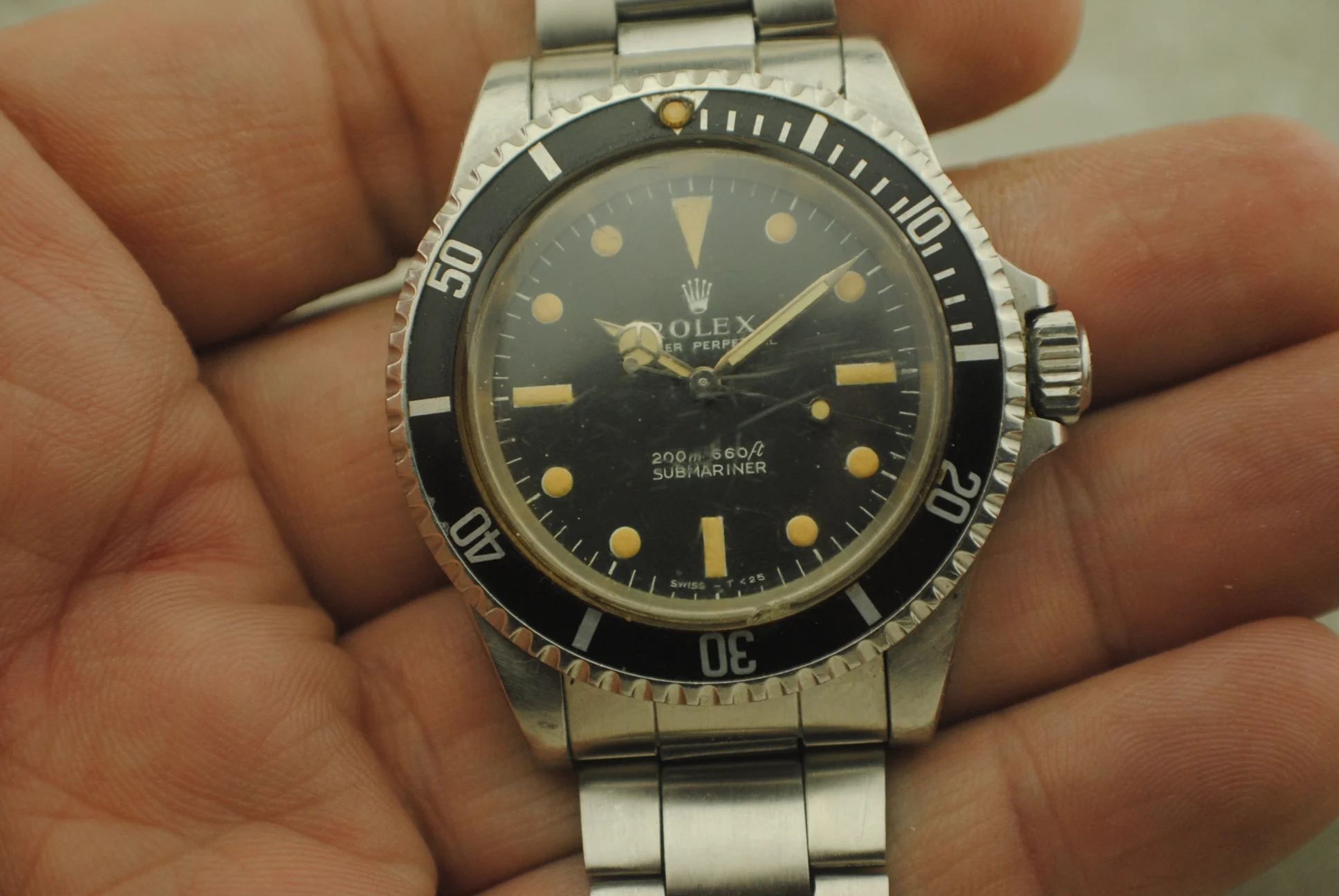 In-hand front detail of the Rolex Submariner 5513 showing its matte dial, bezel insert, crown and bracelet