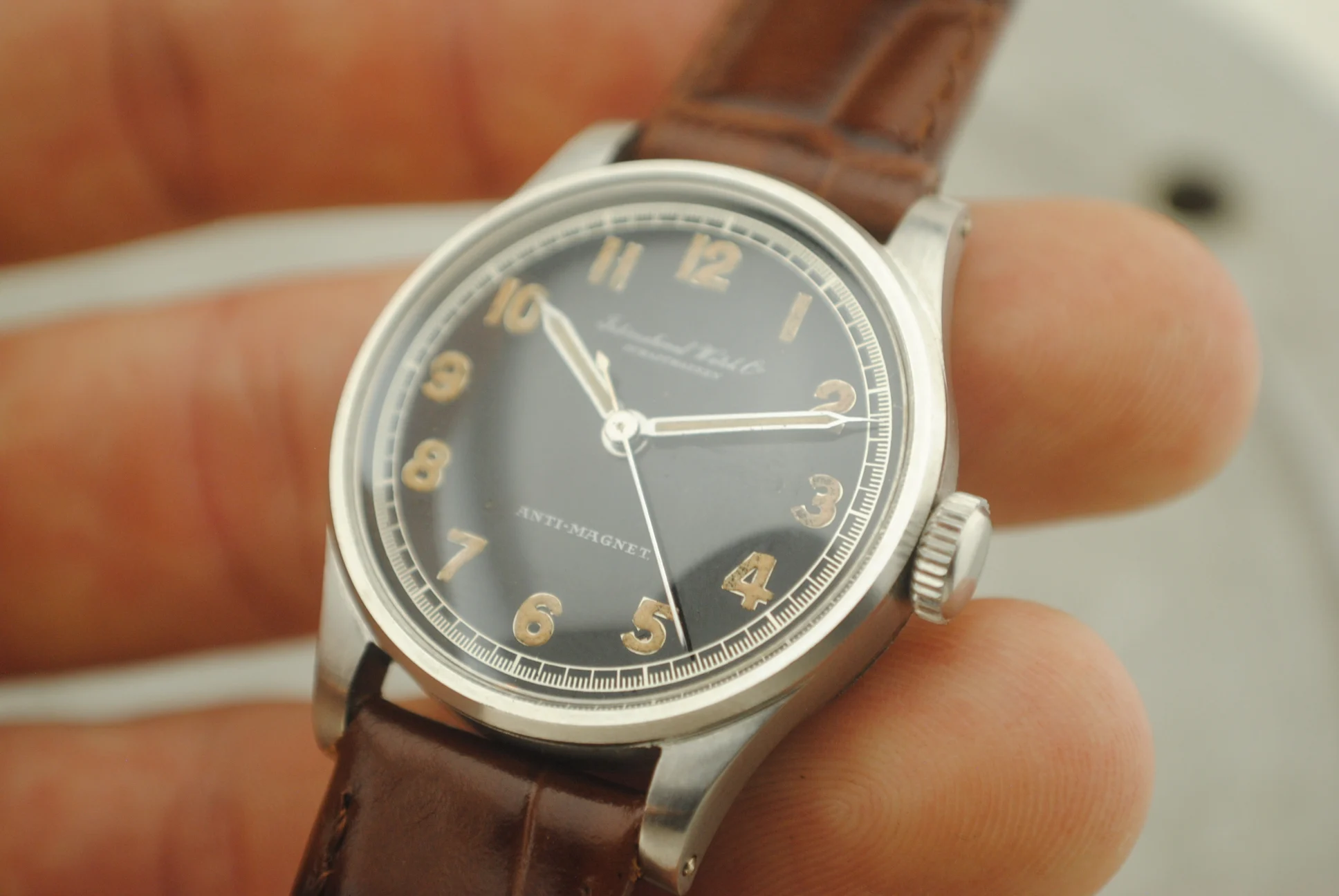 In-hand crystal-on front detail of the IWC Calatrava Hermet showing the dial, crown and case