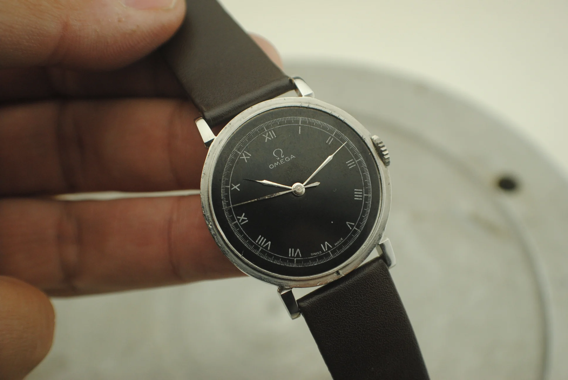 Alternate handheld crystal-on angle of the Omega CK2015 Fagiolino black dial and case