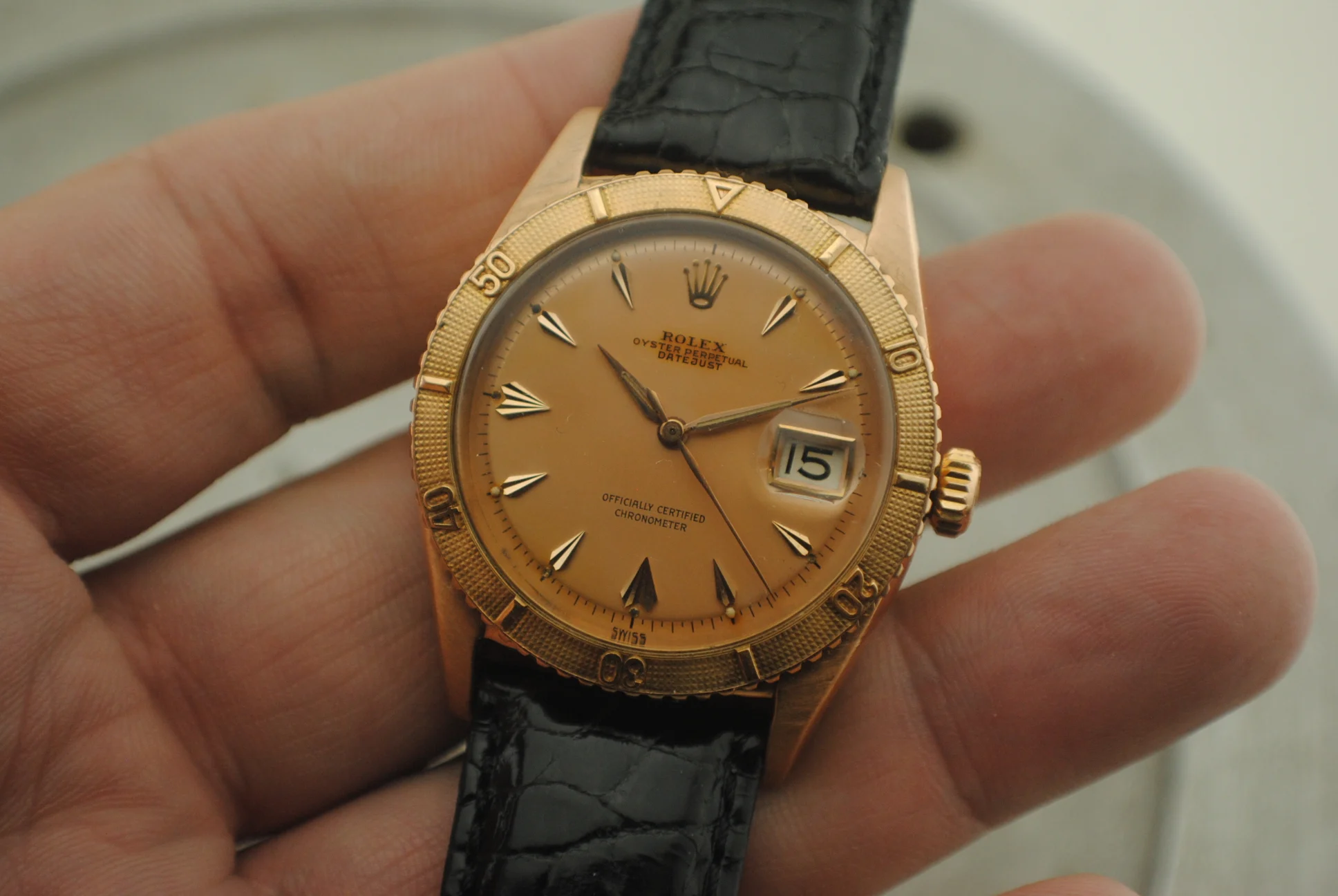 Alternate crystal-on in-hand front view of the Rolex Thunderbird 6309 with pink gold case and pink dial