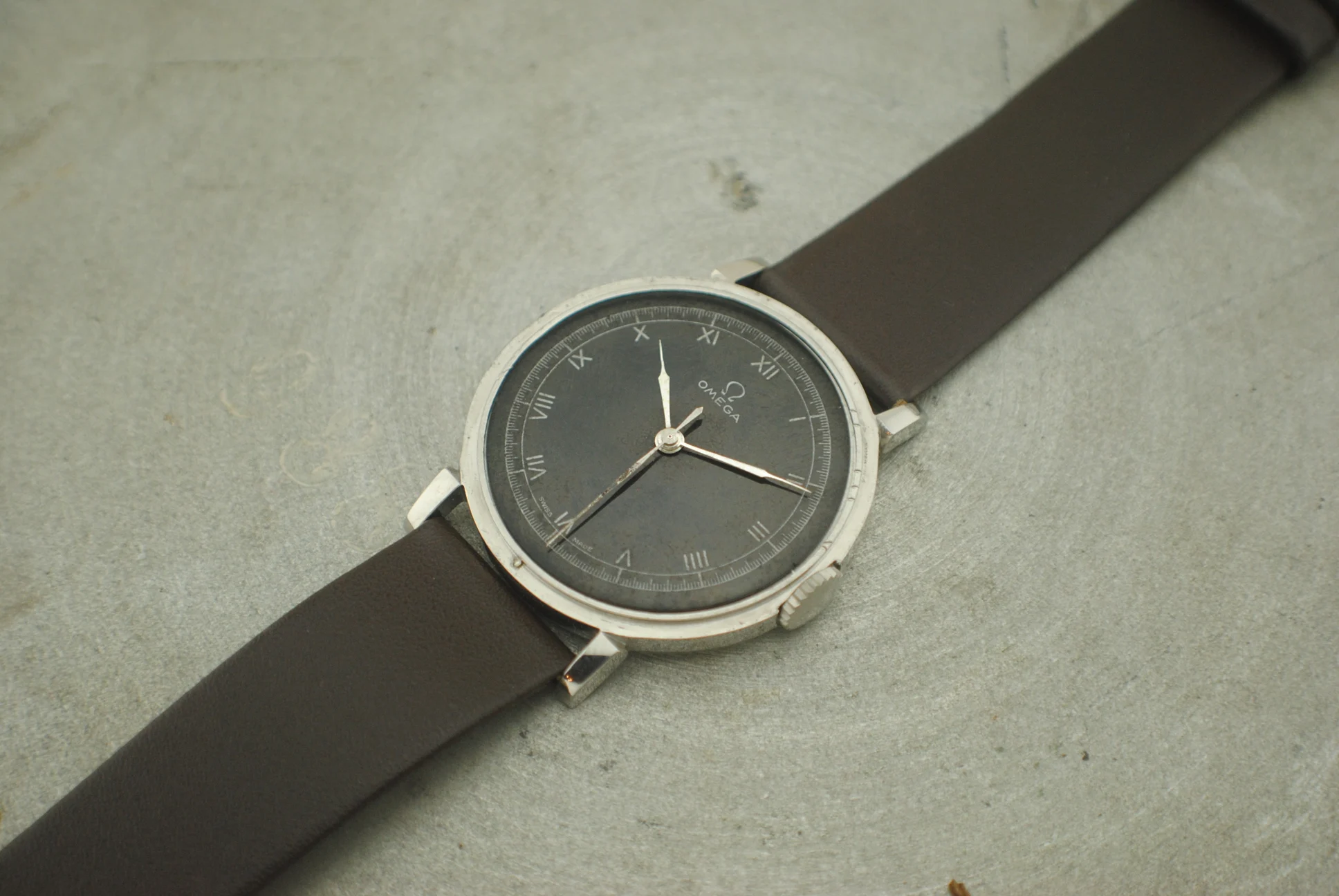 Alternate crystal-on tabletop view of the Omega CK2015 Fagiolino and its black enamel decalque dial