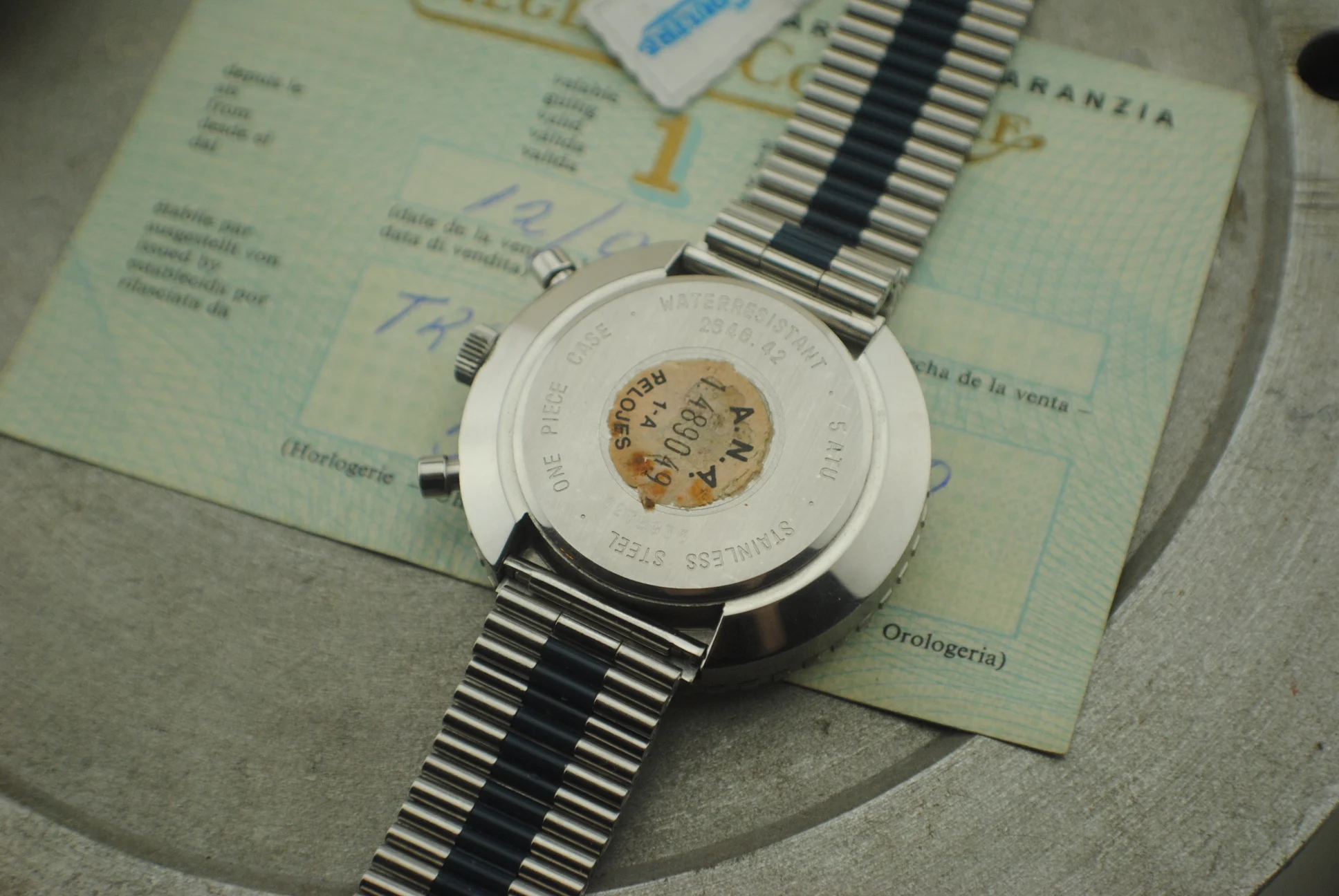 Closed Jaeger-LeCoultre Doctor Pulso caseback with stainless steel engraving and paper sticker, photographed over the warranty papers