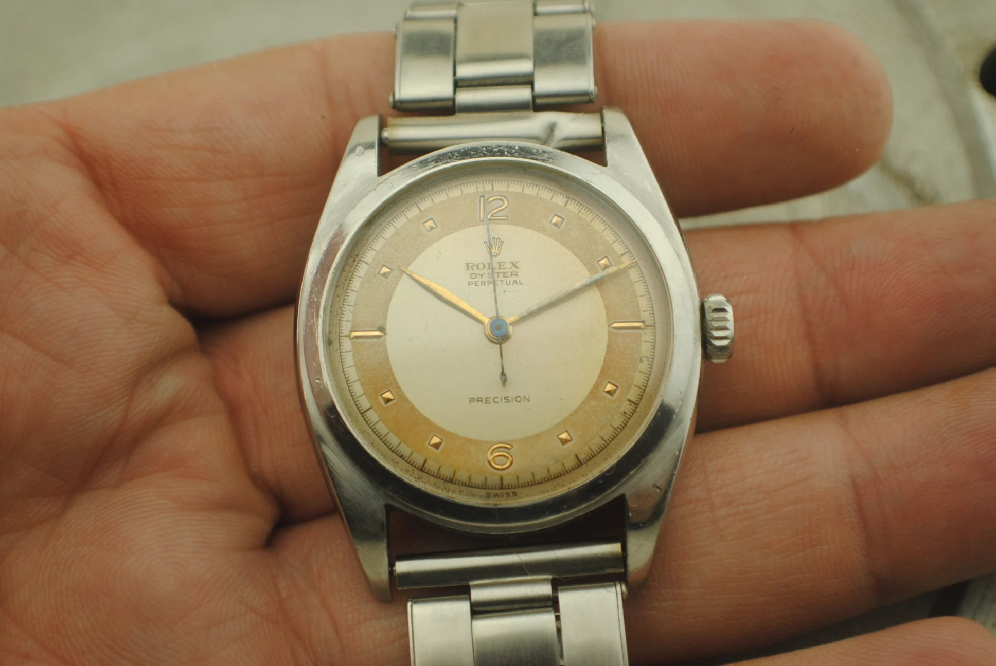 Front view in hand of the Rolex 6098 showing its two-tone dial, recessed indexes and numerals at twelve and six