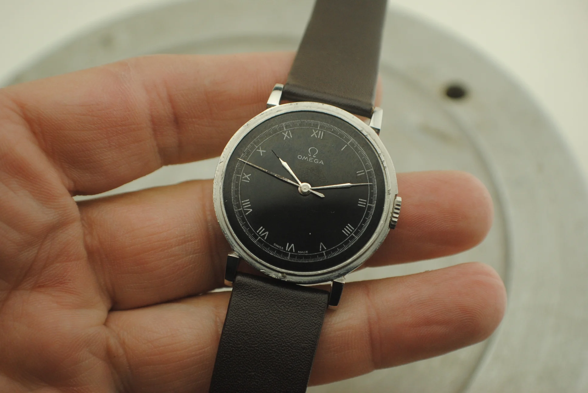 Handheld crystal-on front view of the Omega CK2015 Fagiolino showing Roman numerals and central seconds hand