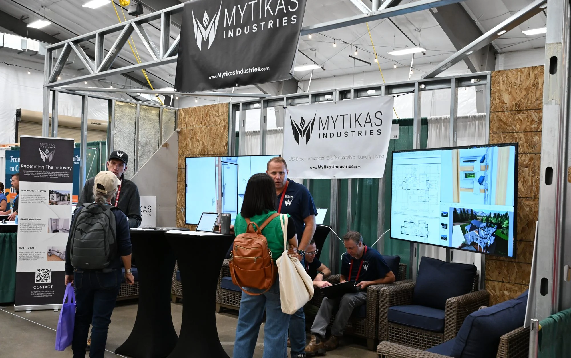 Mytikas representatives speaking with visitors beside cabin displays at The Glamping Show