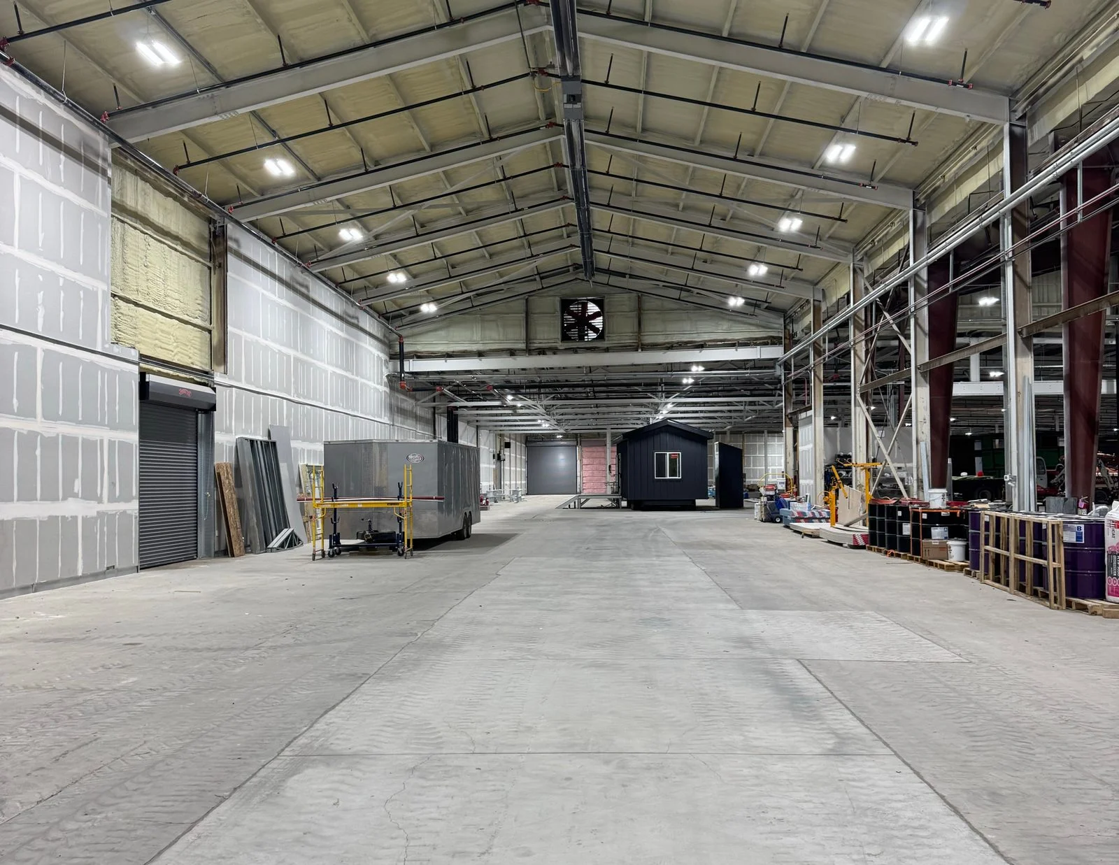 Long factory bay with exposed steel beams and a concrete floor