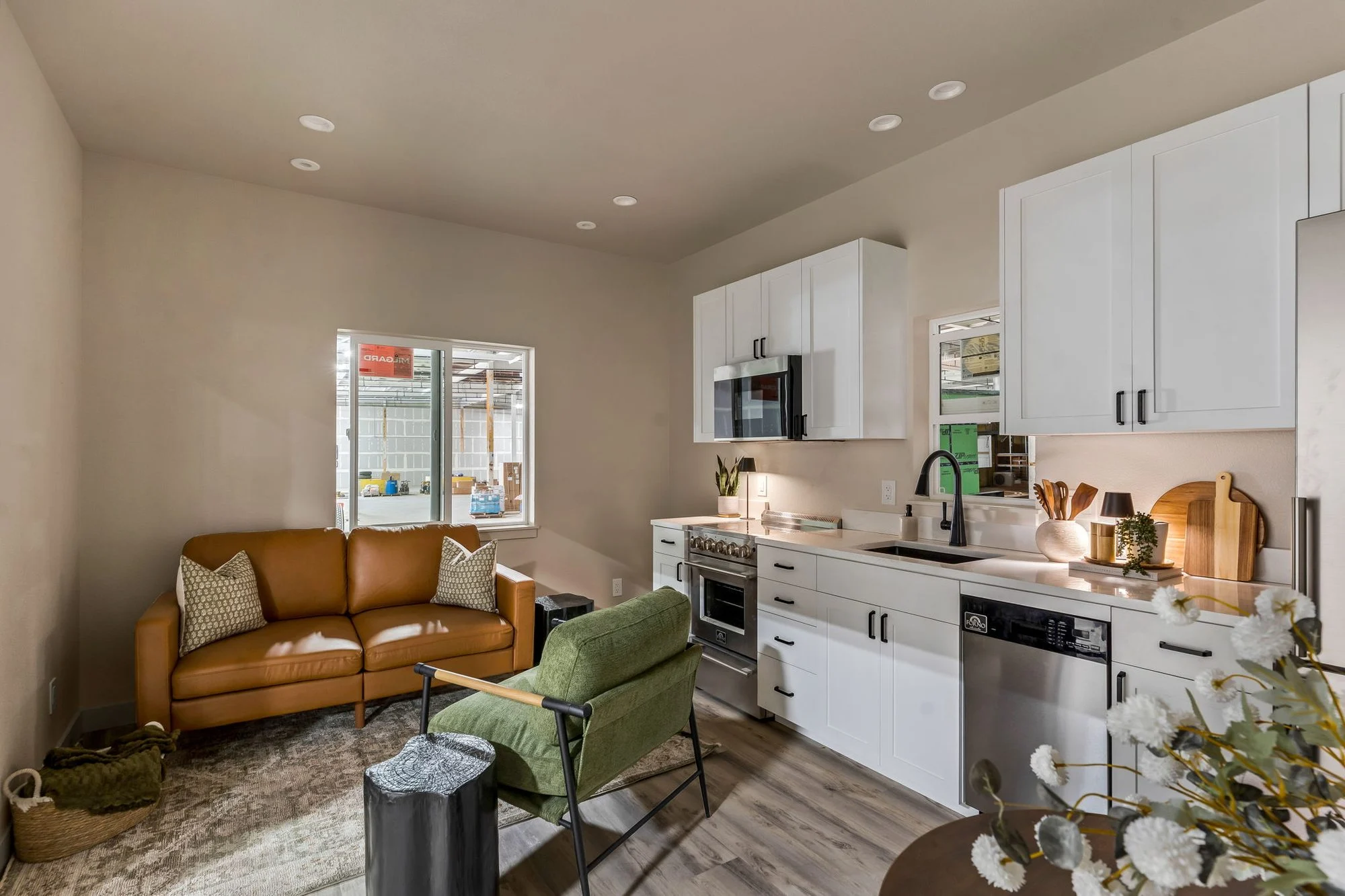 Basecamp living area with a sofa, green armchair and white kitchen cabinetry