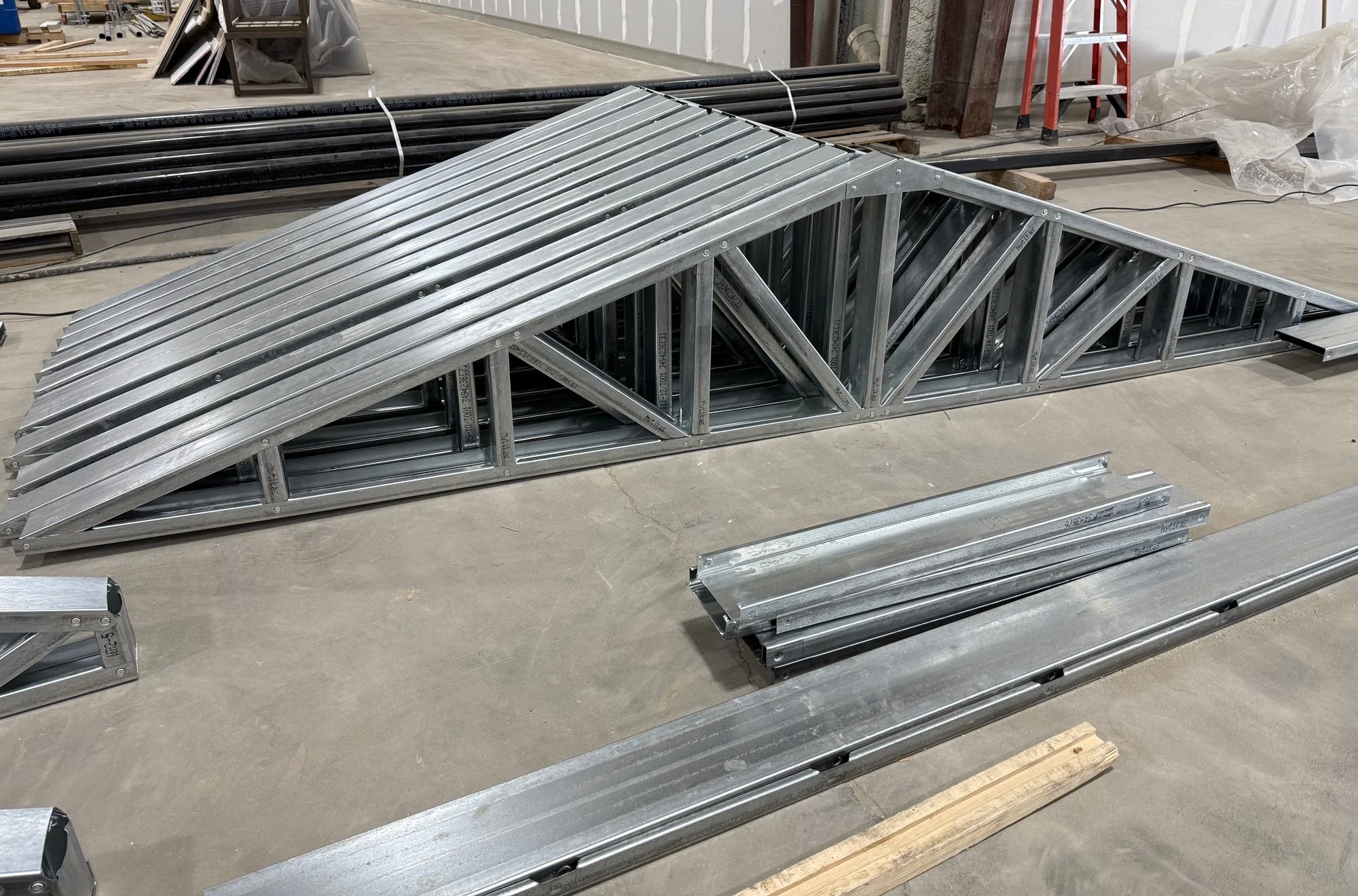 Stacked galvanized steel roof trusses on the factory floor