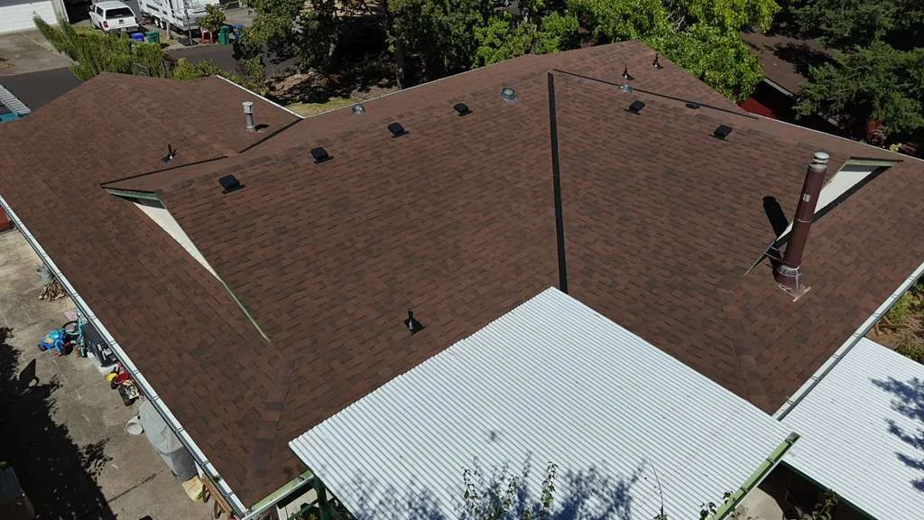 Aerial of the completed brown shingle roof showing sealed valleys and a new pipe flashing