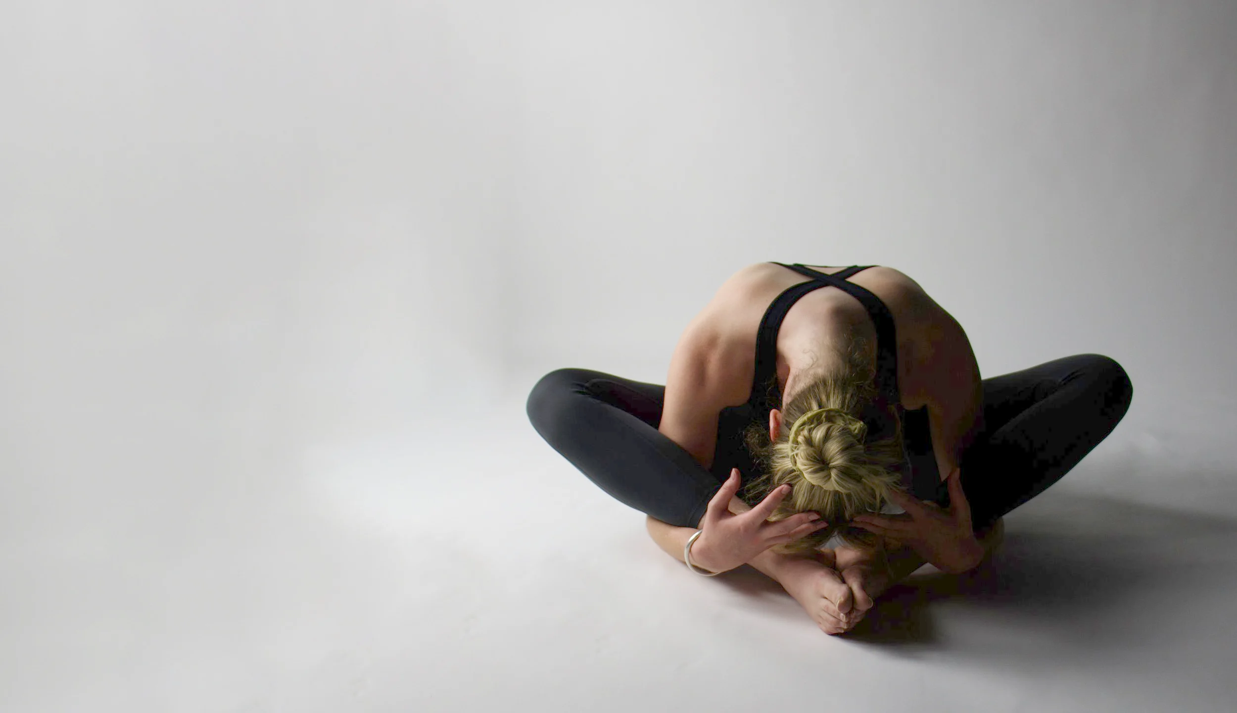 A student folded forward in a seated yoga stretch