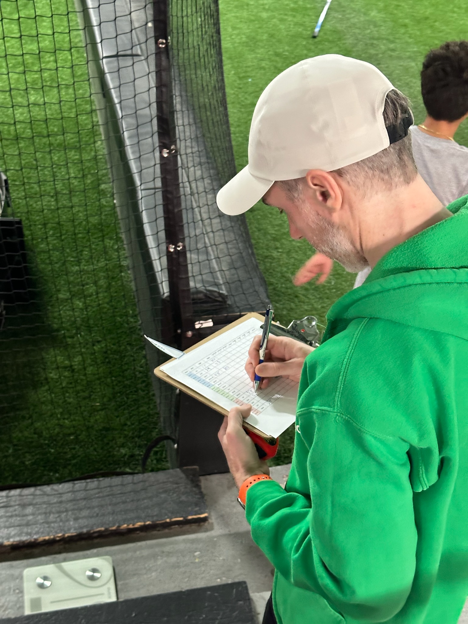 A HeyCoach trainer recording results on a color-coded normative scoresheet