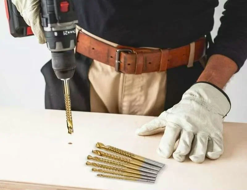 A titanium side-cutting saw drill making a hole in plywood, with a six-size set on the bench