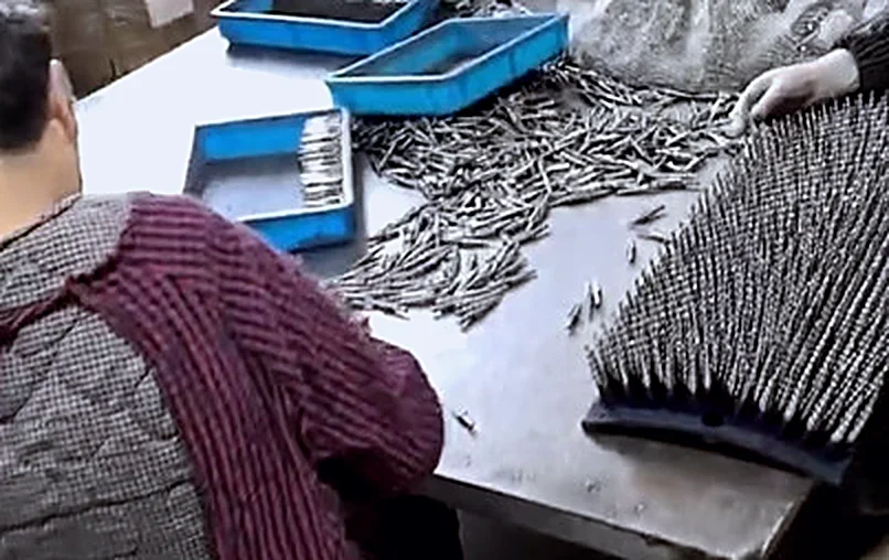 Workers sorting and checking drill bits by hand at a bench