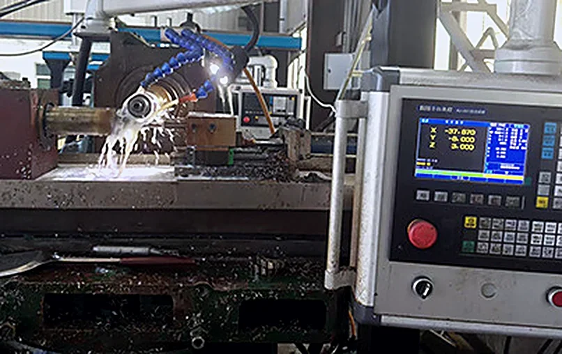 CNC grinder cutting a bit under coolant, with its control screen