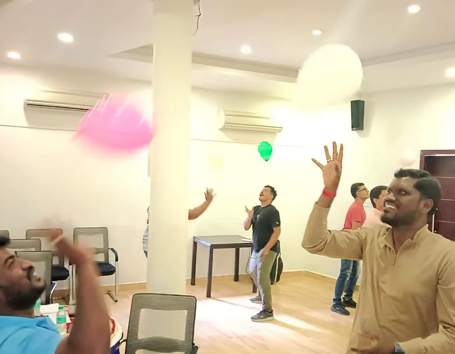 Workshop participants laugh as they keep balloons in the air during a team game