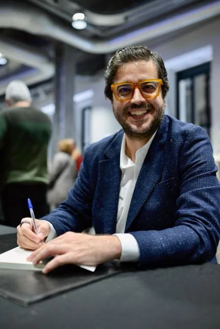 Rafael Tamames sonriendo mientras firma un libro
