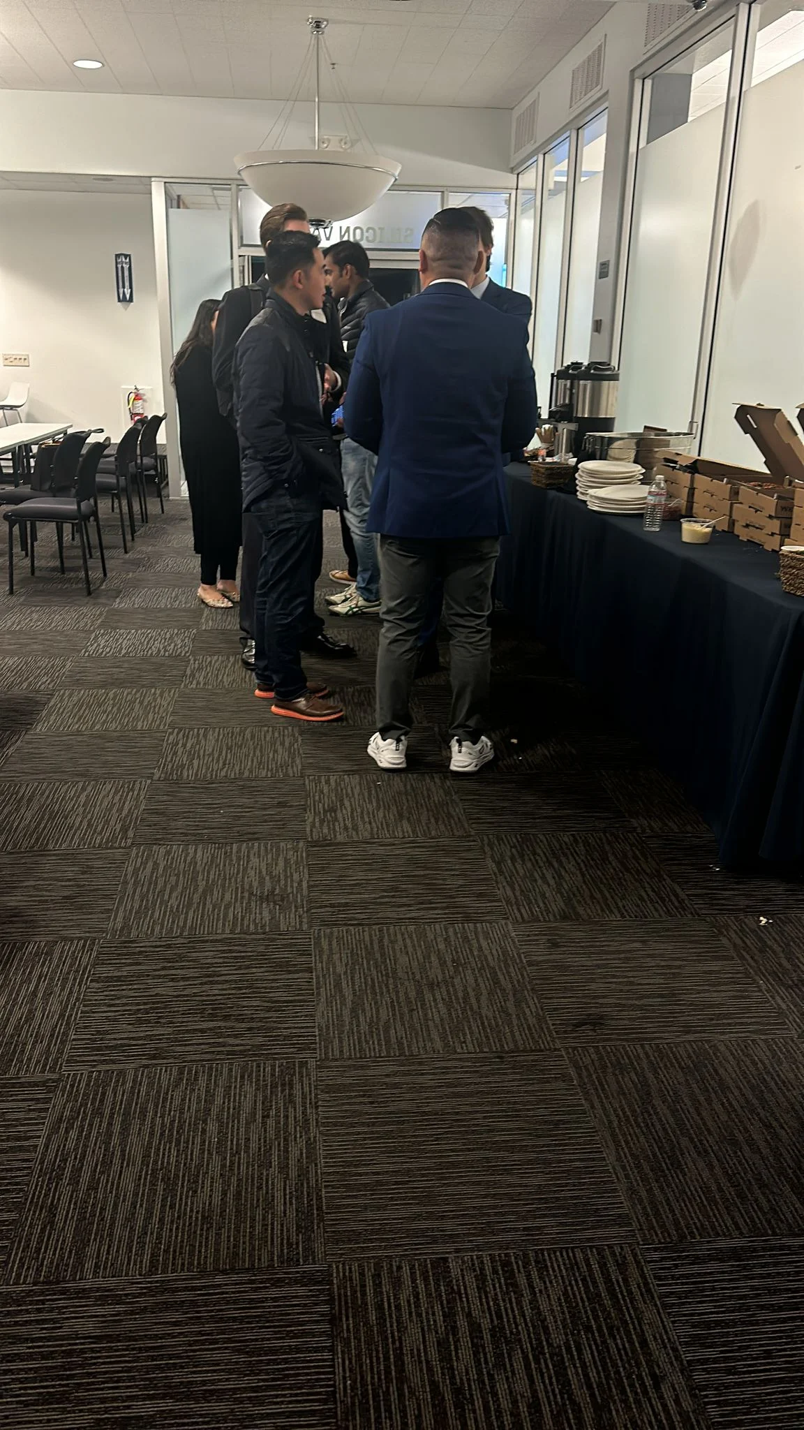 Participants talking beside a refreshments table in the meeting room.