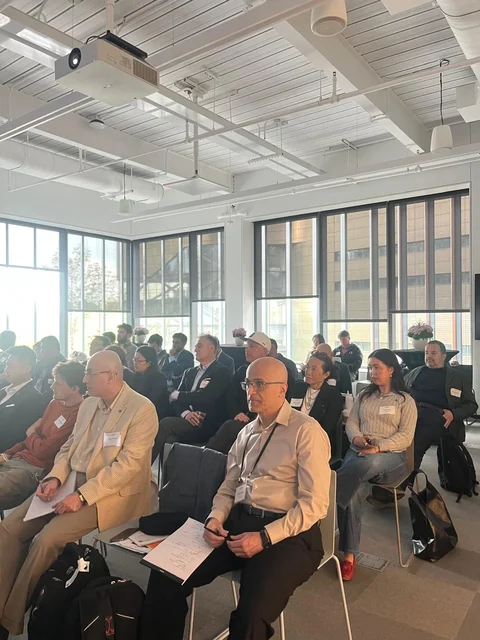 Audience seated in rows beside tall windows at Cornell Tech.