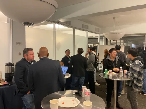 Small groups talking beside high tables and refreshments.
