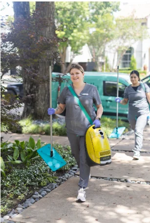 Two Vella’s staff members are entering a Texas home with cleaning equipment and cleaning solutions.