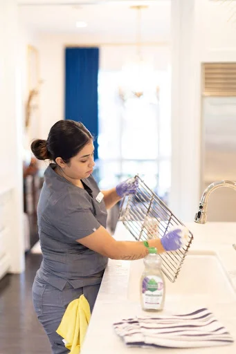 Vella staff member cleaning stainless steel racks with eco-friendly supplies in a Dallas kitchen.