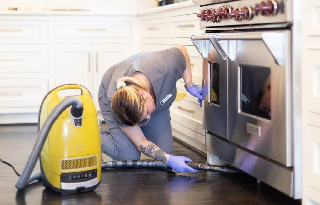 A professional cleaner vacuuming under a microwave A professional cleaner vacuuming under a microwave, demonstrating how to clean your microwave effectively and maintain a tidy kitchen