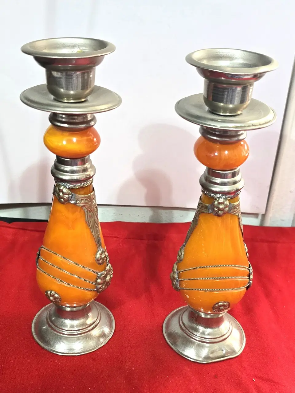 זוג פמוטי שבת מרוקאיםי, עשויים זכוכית בצבע ענבר ופיוטר(ייתכן חומר שרף כלשהו, לא נבדק לעומק), עבודת יד.   מעוטר בקישוטי מתכת וחוטי מתכת דקים כרוכים סביב הפמוטים.