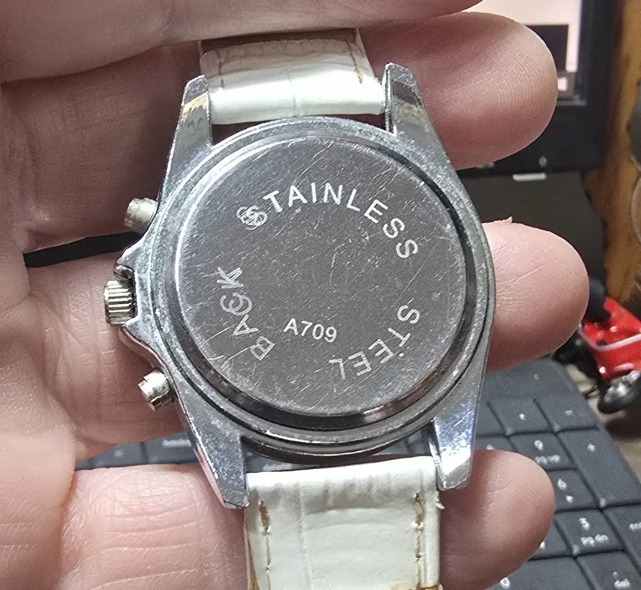 שעון יד חדש לגמרי הלוח מעוטר בשיבוץ צפוף של אבנים קטנות השעון עשוי ממתכת בגוון כסף רצועת עור לבנה דמוי עור תנין