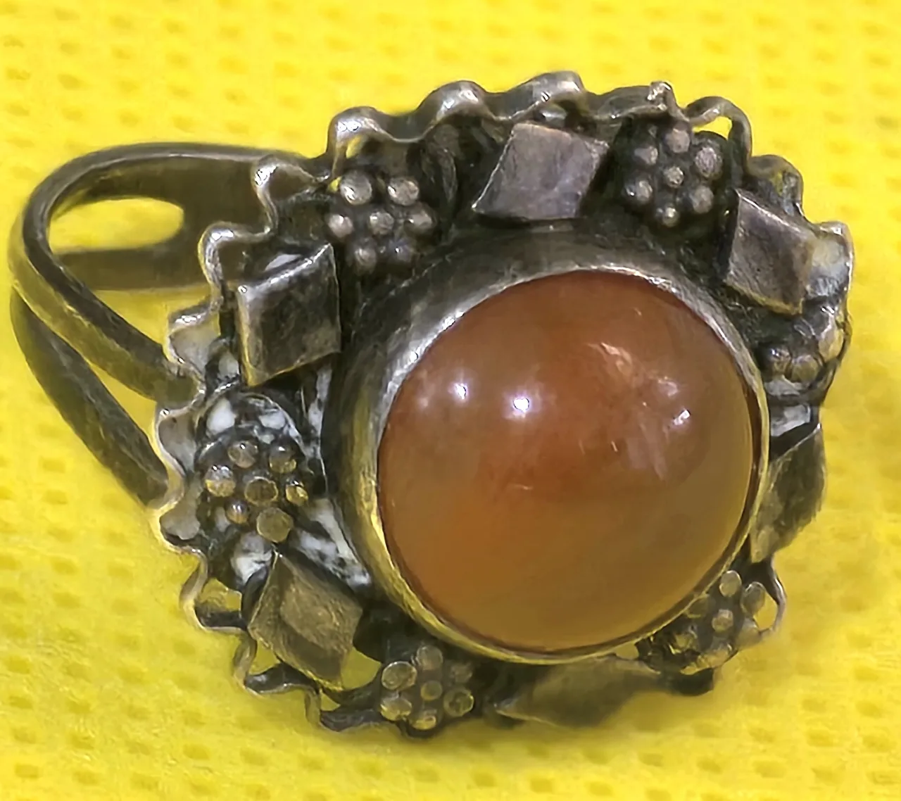 טבעת כסף עדינה ויפה, משובצת אבן אגת ומעוטרת מסביב בדוגמאות פרחים ומעוינים קטנים.  לא נמצאה חתימה.  מידת הטבעת: מתכווננת  משקל: 4.18 גרם.