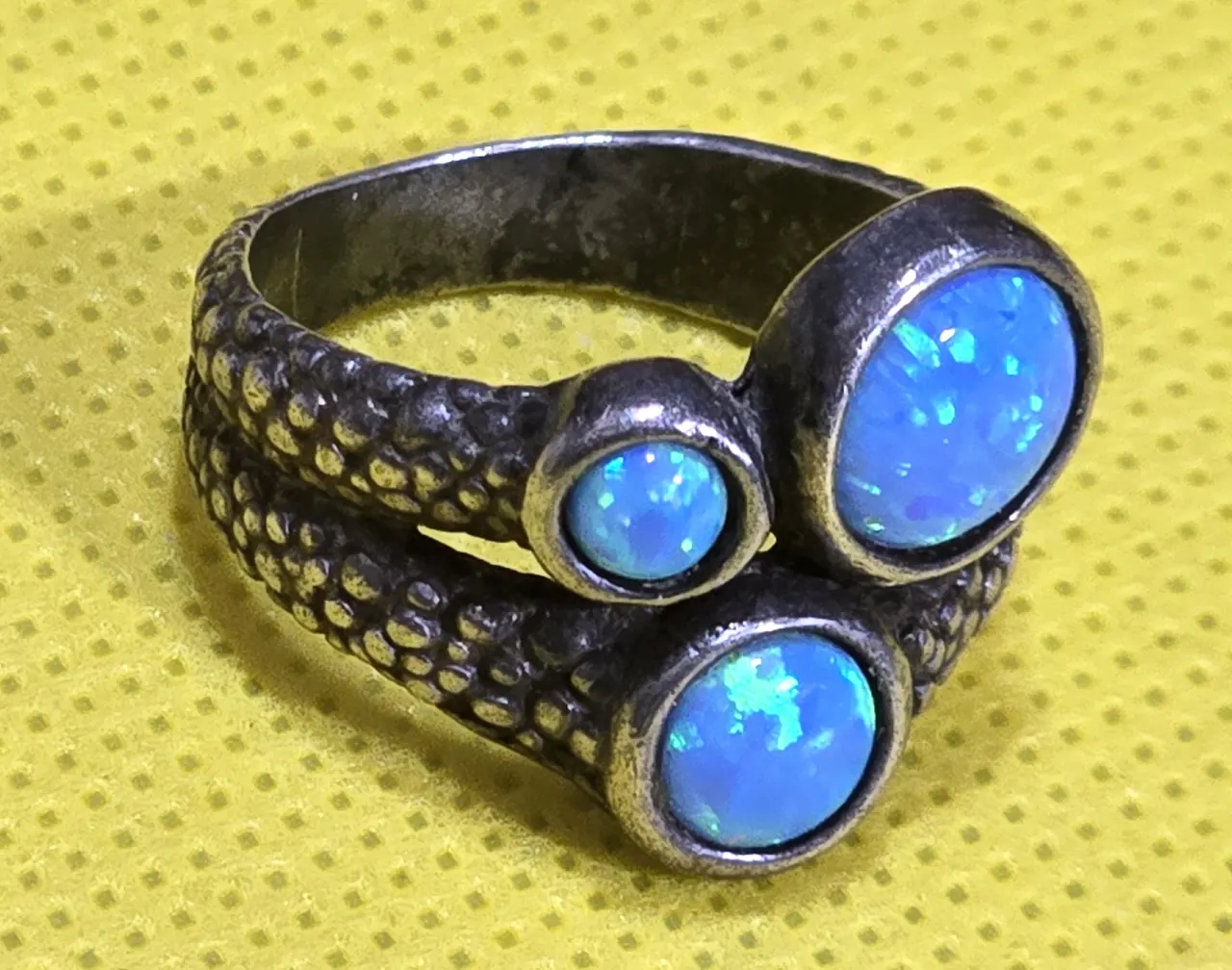 טבעת כסף 925 של חברת שבלול חתומה, משובצת בשלושה אבני אופל בחיתוך קבושון, מעוטרת דמוי עור נחש, מידה 8 חדשה.