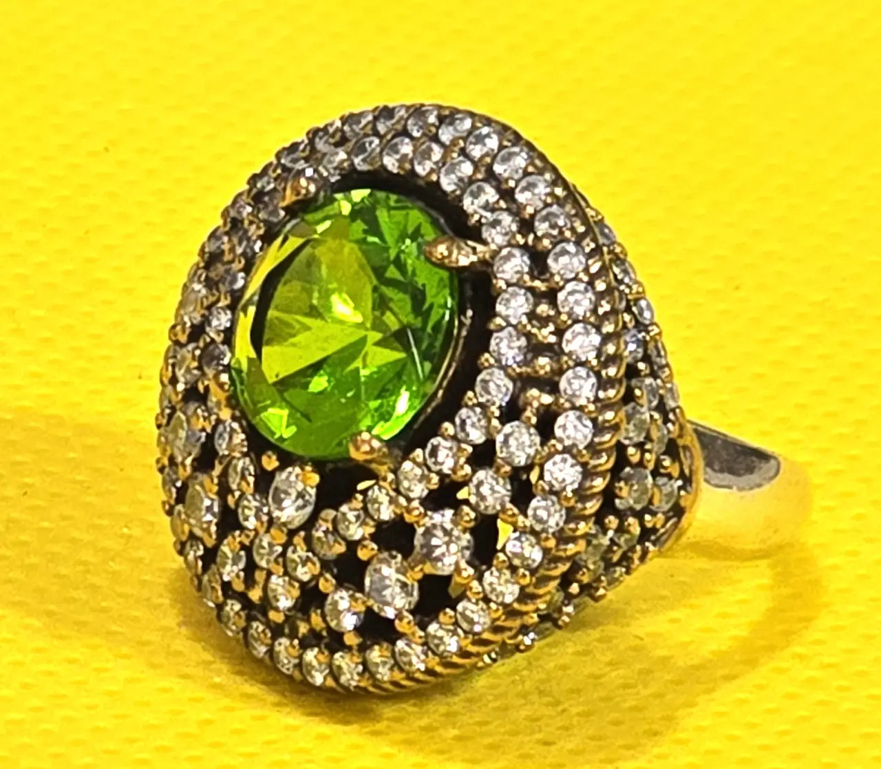 טבעת כסף 925 חתומה מידה 7\7.5 אבן מרכזית זו אבן פרידוט ומסביב אבני סברובסקי יש נגיעות של זהב