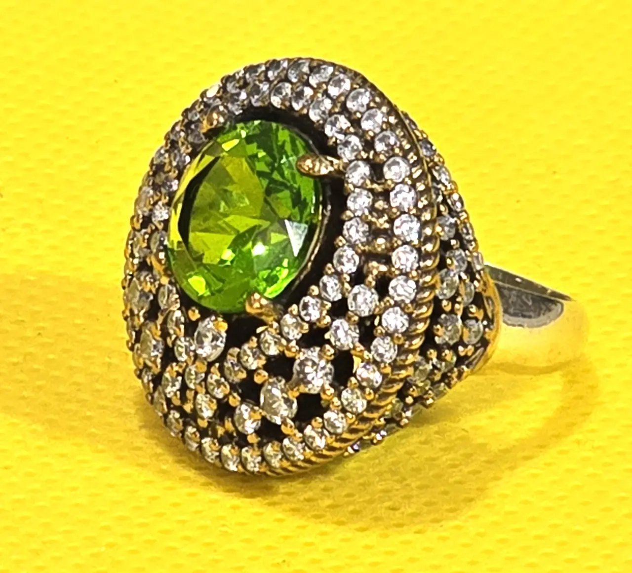 טבעת כסף 925 חתומה מידה 7\7.5 אבן מרכזית זו אבן פרידוט ומסביב אבני סברובסקי יש נגיעות של זהב