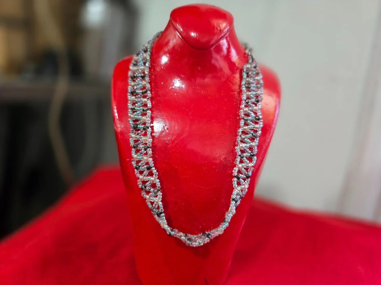 שרשרת בסגנון צ'וקר (Choker) או שרשרת קולר עשויה בעבודת יד חרוזי ונציה קטנים בגוון לבן שחור ואדום התכשיט מאופיין בדוגמת אריגה