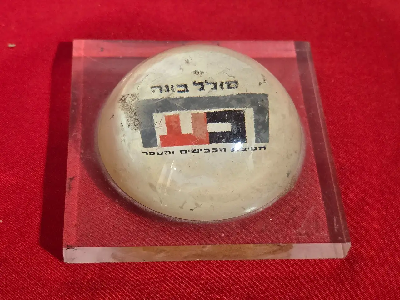 משקולת נייר שהיא גם פרסומת  סולל בונה  חטיבת הכבישים והעפר . תוצרת הצבי -  קיבוץ מעיין צבי . שריטות ...  מידה 9.5 על 9.5 על 4 סמ