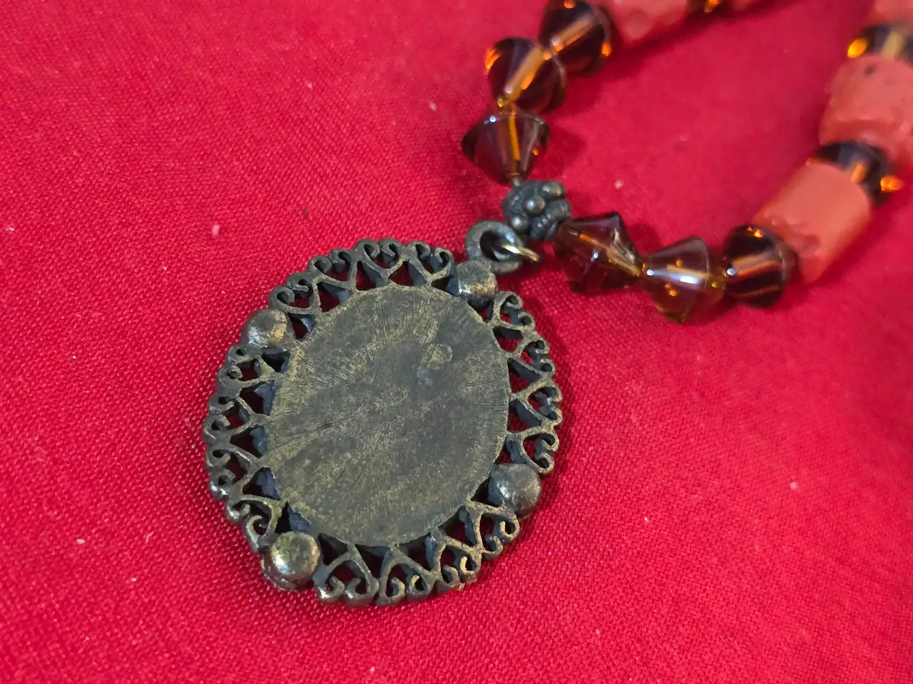 שרשרת בסגנון עתיק עם תליון המציג דמות נסיכה עשויה מחרוזי אלמוג אדומים בצורת גליל וחרוזי גראנט כהים יותר שמפרידים בינהים