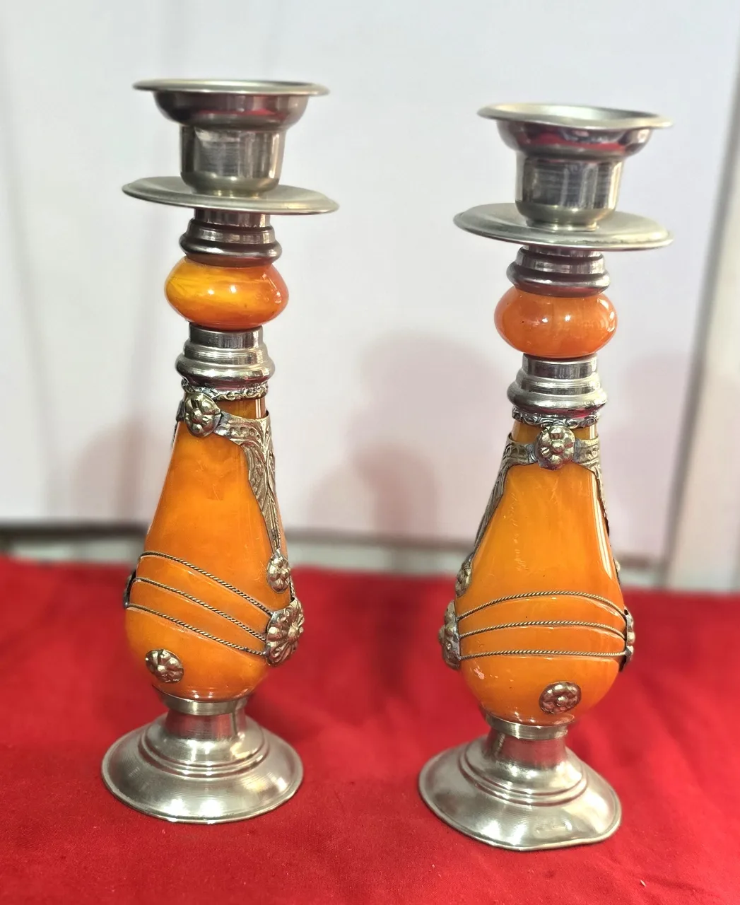 זוג פמוטי שבת מרוקאיםי, עשויים זכוכית בצבע ענבר ופיוטר(ייתכן חומר שרף כלשהו, לא נבדק לעומק), עבודת יד.   מעוטר בקישוטי מתכת וחוטי מתכת דקים כרוכים סביב הפמוטים.