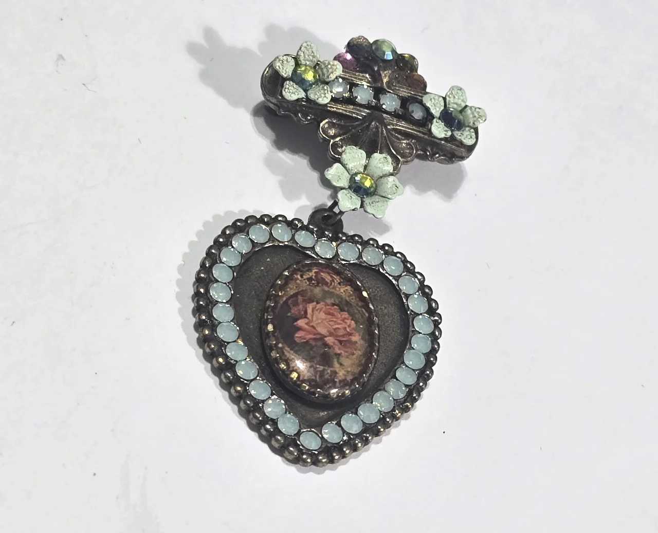 סיכה מבית מיכל נגרין חלק תחתון צורת לב באמצע אמאייל שבתוכו ורד ומסביב אבני סברובסקןי ירוקים חלק עליון פרחים עם אבני סברובסקי נדירה