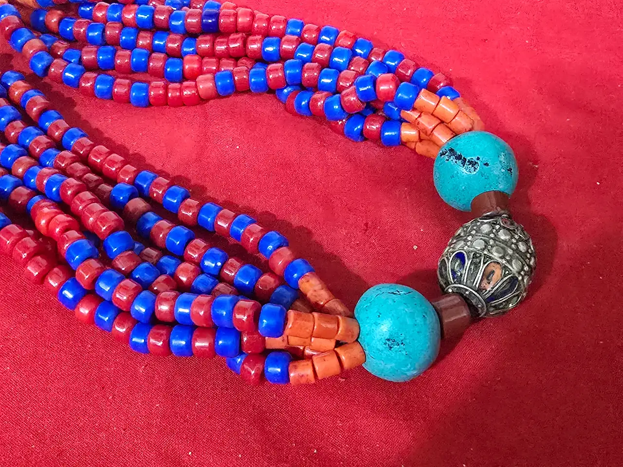 שרשרת תכשיט מרשים בסגנון אתני טיבט נפאל או צפון אפריקה השרשרת מורכבת מריבוי שורות של חרוזים קטנים בצבע אדום וכחול עזים חרוזי טורכיז בחלק התחתון